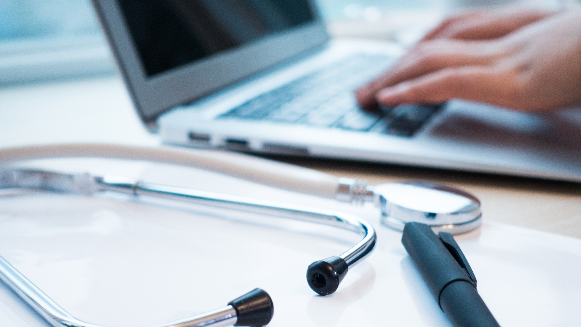A healthcare professional typing on a keyboard.